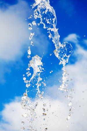 water drops from the fountain against blue summer skyの写真素材
