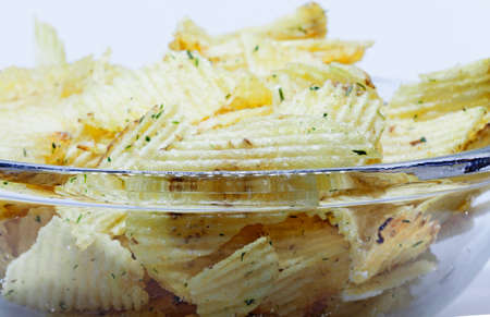 A glass bowl with potato chips on white