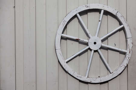 an old wagon wheel mounted on a white wooden wallの写真素材
