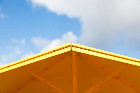 the edge of a yellow parasol with blue sky in the background