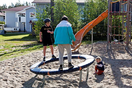 Umea, Norrland Sweden - September 19, 2020: three children play with a big wheel in a sandboxのeditorial素材