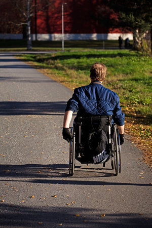 Umea, Norrland Sweden - October 25, 2022: man in wheelchair rides on asphalt roadのeditorial素材