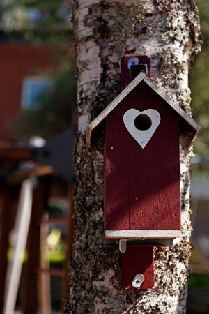a red birdhouse with a white heart by the holeの写真素材