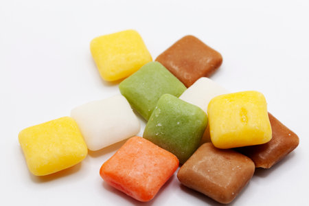 An assortment of colorful cube-shaped candies in yellow, green, brown, and orange hues creates a...