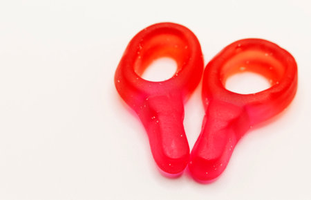 two bright red ring-shaped gummy candies on white background