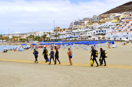 Los Cristianos beach, Tenerife, Canary Islands, Spain, Europe - June 13, 2016: Scuba divers on the beach walking to the seaのeditorial素材