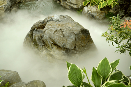 A fountain in a rocky water feature covered in mistの写真素材