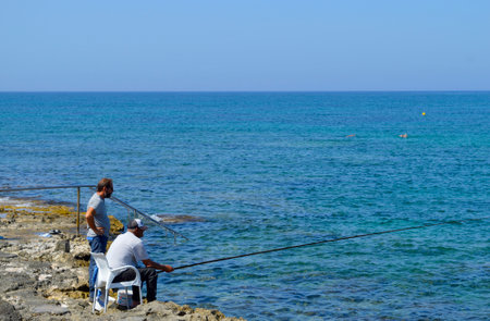 Two men fishing from Paphos harbour a popular tourist resort in Cyprusのeditorial素材