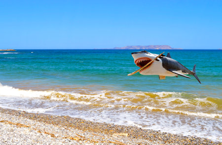 Shark jumping out of the sea with a surfboard in its mouth off Kato Gouves pebble beach in Creteの写真素材