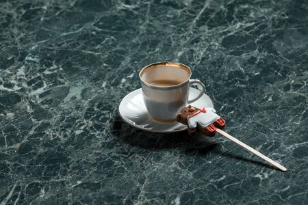 black coffee with cookie bear on stick on saucer on green marble backgroundの写真素材