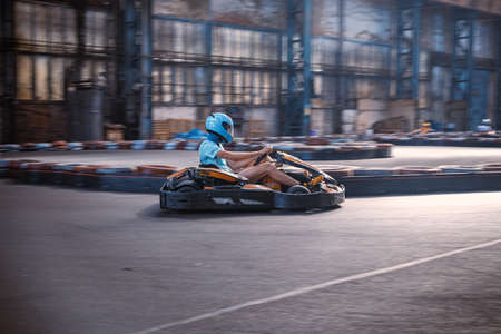 Male driving a kart through a turn on an indoor track