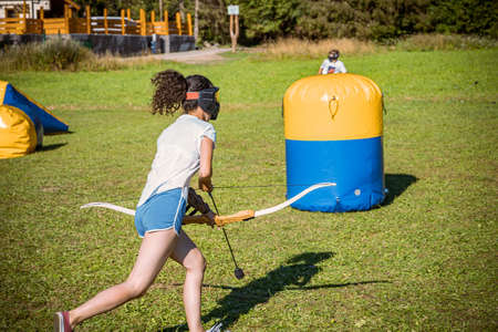 teenage girl running with bow and arrow during a game of archery tagの写真素材