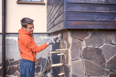Young man helping with building a rock facade on a houseの写真素材