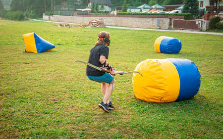 Young man preparing for an attack while playing archery tagの写真素材