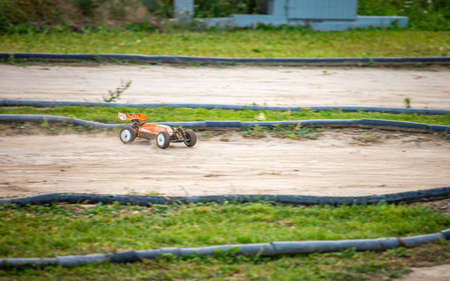Orange RC buggy going quickly throuh a turn on an outdoor trackの写真素材