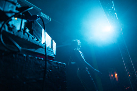 Young man performing live music on stage with lights and smoke in nightclubの写真素材