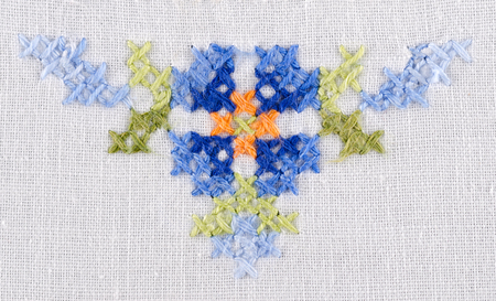 Blue flower triangle motiv hand embroidery on white linen tablecloth.  Multicolored cross stich...