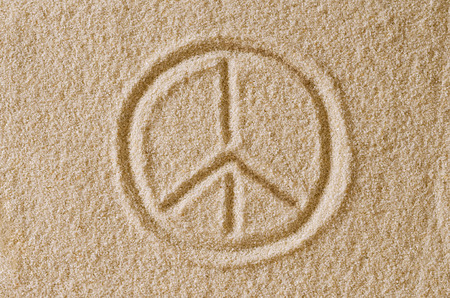 Peace Sign drawn in sand. Imprint and shape of the Pace Symbol in ocher grains of sand. Also a symbol for antiwar, love and counterculture, also used by hippies. Macro photo close up from above.の写真素材