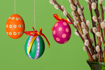 Paschal eggs on willow bouquet with catkins, horizontal on green background. Three hand painted...
