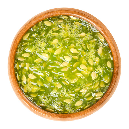 Kiwano pulp in wooden bowl. Lime green, jelly-like flesh of horned melon, also African horned cucumber, jelly melon, hedged gourd or melano. Cucumis metuliferus. Macro food photo from above over whiteの写真素材