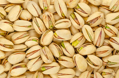 Roasted and salted pistachio seeds with shell, background, from above. Snack food, made from fruits...