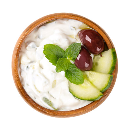 Tzatziki, Greek dip sauce in a wooden bowl. Appetizer and side dish made of strained yogurt, mixed with cucumber, garlic, salt, olive oil, garnished with kalamata olives and mint.の写真素材