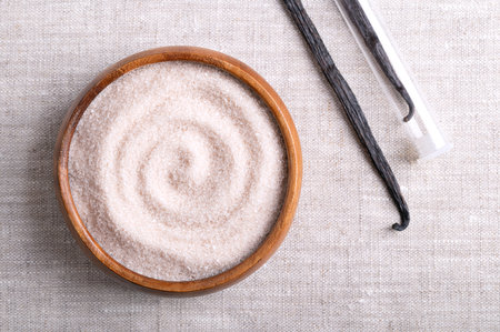Vanilla sugar, flavored sugar in a wooden bowl on linen fabric, next to dried, brown, ripe pods or beans of Vanilla planifolia, a spice with distinctive flavor, used for baking andの写真素材