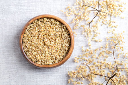 Dried elderflowers in a wooden bowl on linen fabric, with dried corymbs on the right. Elderflower tea, Flos Sambuci, blossoms of European black elder, Sambucus nigra.の写真素材