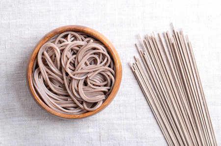 Chilled and boiled soba noodles in a wooden bowl on linen fabric. Thin Japanese noodles, made primarily from buckwheat flour, with wheat flour mixed in.の写真素材
