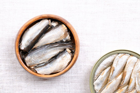 Sardines, with skin and bones, in vegetable oil, in a wooden bowl, on linen. Canned, wild caught sardines, or pilchards, Sardina pilchardus, a small and oily fish.の写真素材