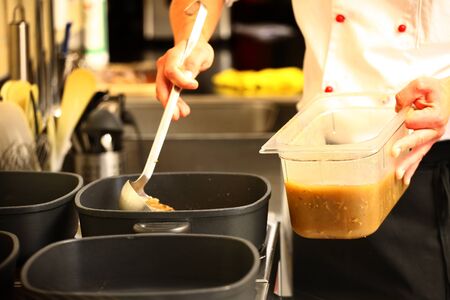 professional cook in kitchen preparing food for customers showing hands and a cook grabbing some saucesの写真素材