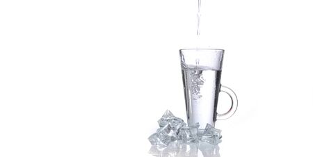 glass of fresh clear water with ice on white backgroundの写真素材