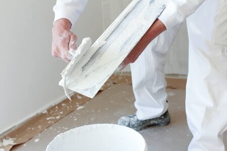 Plasterer stirring plaster in a bucket. With hands and legs showing