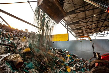 garbage pile getting sorted for recycling of materials with a tractorの写真素材