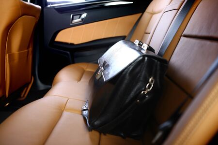 business leather briefcase on backseat of luxury car with back litの写真素材