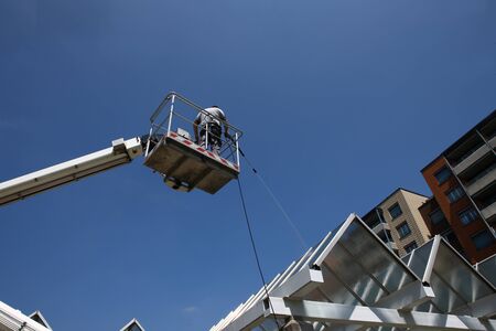 worker of Professional Facade Cleaning Services washing a glass roof with blue skyの写真素材