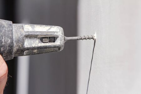 Plasterer screwing to a wall, With white copy spaceの写真素材