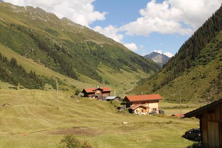 swiss alp stable on farm land with hut and blue skyの写真素材