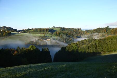 foggy valley in switzerland during sunrise with fog in the valleyの写真素材