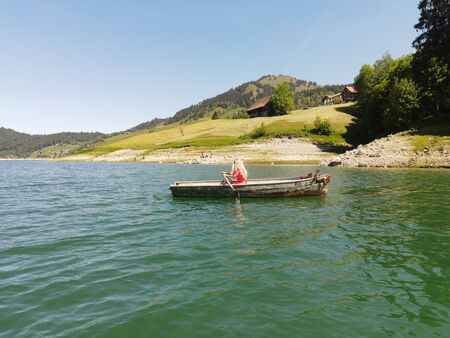 woman with long blond hair on boat with roses and flowers on blue lakeの写真素材