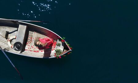 woman with long blond hair on boat with roses and flowers on blueの写真素材