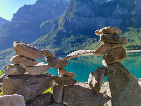 Stones stacked on top of each other with lake and mountain backgroundの写真素材