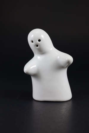  white  ceramic doll standing on black background の写真素材