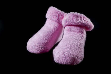 Pink baby socks on black background.