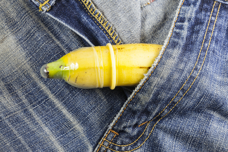 Condom and banana ready for safe sex on jeans background.の写真素材