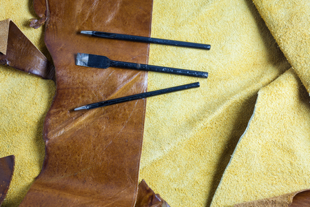 Leather sewing tools on a real leather background.