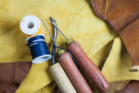 Leather sewing tools on a real leather background.