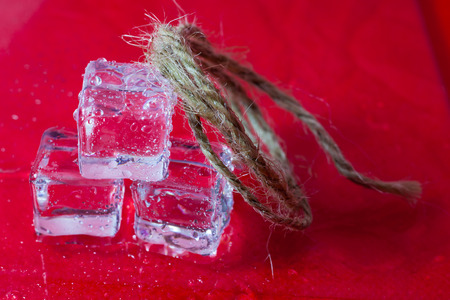 Shining ice cubes on red background.の写真素材