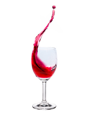 Red wine splash into glass on white background.の写真素材