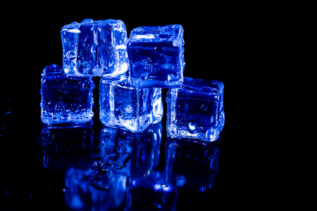ice cubes in blue light on a black table.の写真素材
